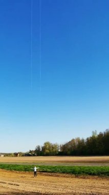 Mutlu çocuğun dikey videosu tarlada rüzgarla oynayarak gökyüzüne parlak bir gökkuşağı uçurtması fırlatıyor. Yaz konsepti. Okul tatili. Yaşam tarzı. 4k görüntü.