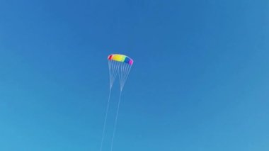 Mutlu bir çocuk, tarlada rüzgarla oynayarak, gökyüzüne parlak bir gökkuşağı uçurtması fırlatır. Yaz konsepti. Okul tatili. Yaşam tarzı. Çocukluk