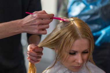 Grodno, Belarus - 20 Ekim 2016: Keune marka teknoloji uzmanı Artem Raychuk, Kolibri güzellik salonuna katılımıyla reklam atölyesindeki bir modelin saçını boyadı.