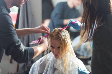 Grodno, Belarus - 20 Ekim 2016: Keune marka teknoloji uzmanı Artem Raychuk, Kolibri güzellik salonuna katılımıyla reklam atölyesindeki bir modelin saçını boyadı.