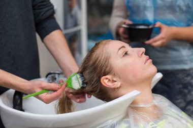 Grodno, Belarus - 20 Ekim 2016: Keune marka teknoloji uzmanı Artem Raychuk, Kolibri güzellik salonuna katılımıyla reklam atölyesindeki bir modelin saçını boyadı.