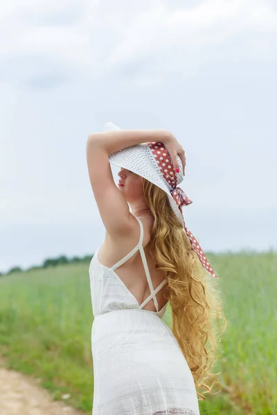 白いドレスの女の子と畑の背景に帽子 帽子の少女は 屋外でリラックスし 楽しく調和のとれたコンセプトを持って立っています — ストック写真