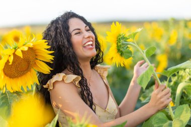 Güzel, gülümseyen, siyah saçlı bir kadının portresi. Ayçiçeğini mikrofon olarak kullanıp şarkı söylüyor.