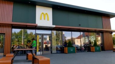 Müşteriler McDonalds restoranına alışverişlerle girip çıkıyorlar.