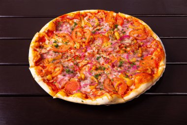 Mozzarella peyniri, göğüs eti, jambon, domates, kırmızı soğan ve ballı bir köy pizzası ahşap bir masada kağıt tabakta servis edilir.