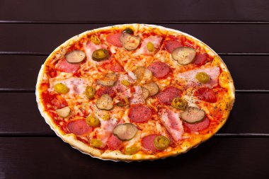 Göğüs eti, kırmızı soğan, turşu, salam, mozzarella peyniri, jalapeno biberi, ahşap bir masada kağıt tabakta servis edilir.