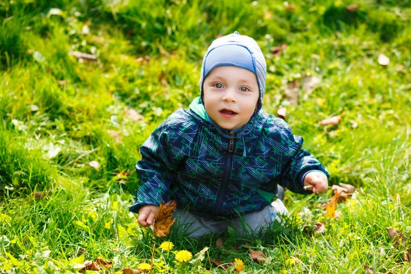 Bonito menino feliz sentado na grama — Fotografia de Stock