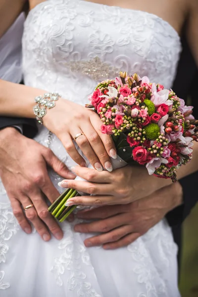 La pareja abrazando y sosteniendo ramo nupcial . — Foto de Stock