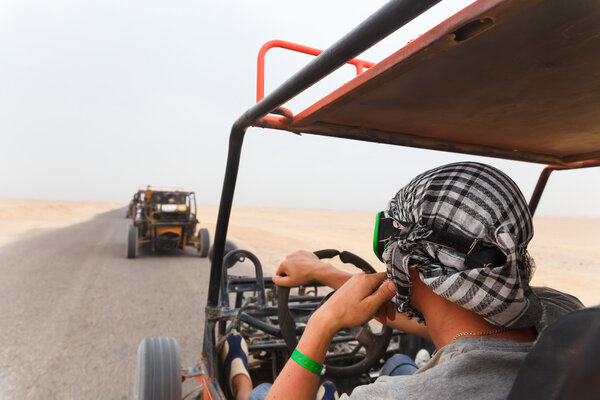 Men riding buggy car in desert 