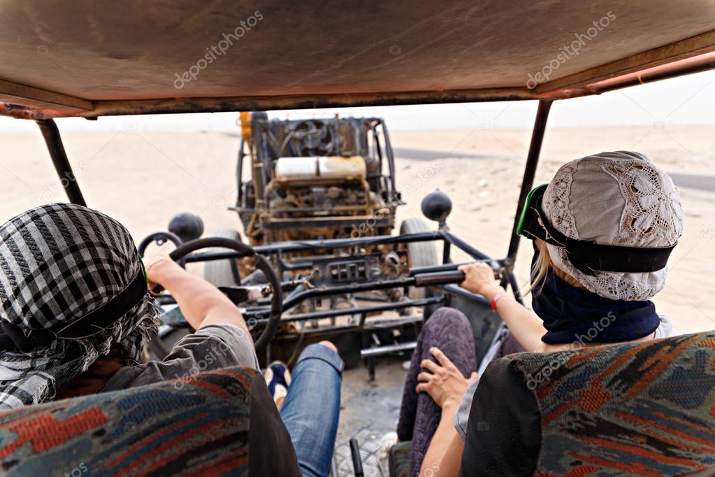 Young couple riding buggy car in desert