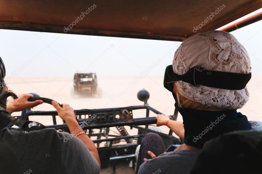 Young couple riding buggy car in desert