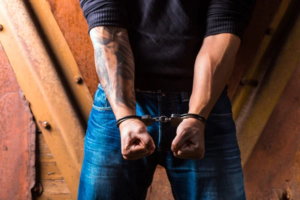 Manos tatuadas de un criminal esposado — Foto de Stock