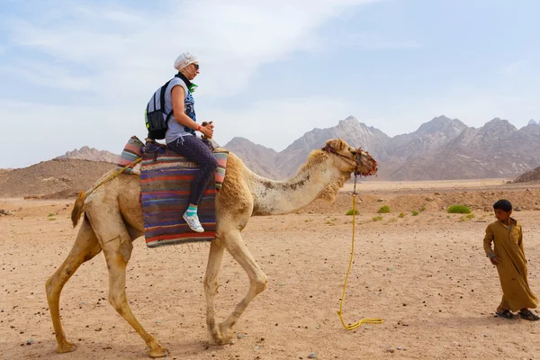 Arabských boy rohlíky turisty na velbloudu. — Stock fotografie