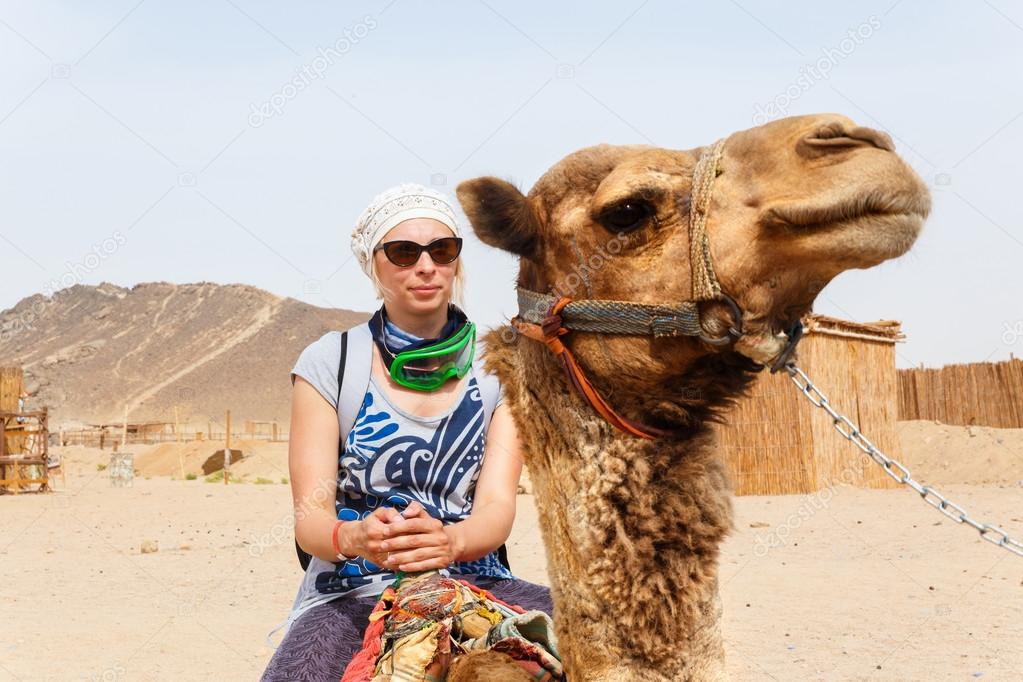 Young caucasian woman tourist riding on camel 
