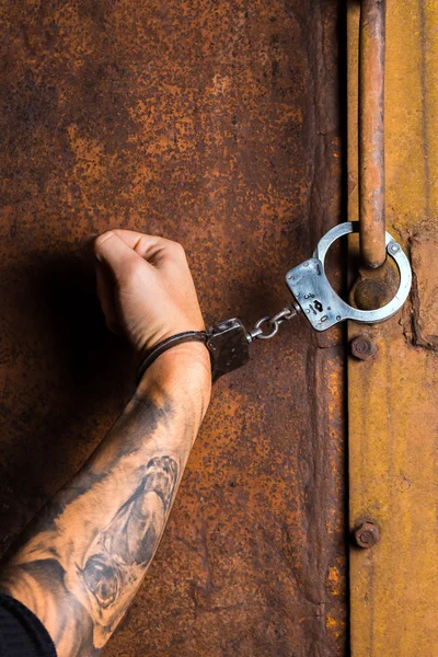 Mão tatuada de um criminoso algemado — Fotografia de Stock