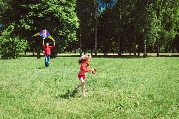 La niña y su padre juegan con una cometa . — Foto de Stock