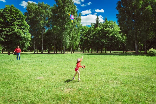 A menina e seu pai brincam com um papagaio . — Fotografia de Stock