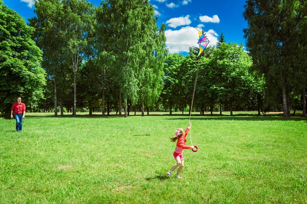 A menina e seu pai brincam com um papagaio . — Fotografia de Stock