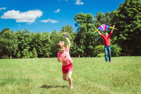 A menina e seu pai brincam com um papagaio . — Fotografia de Stock