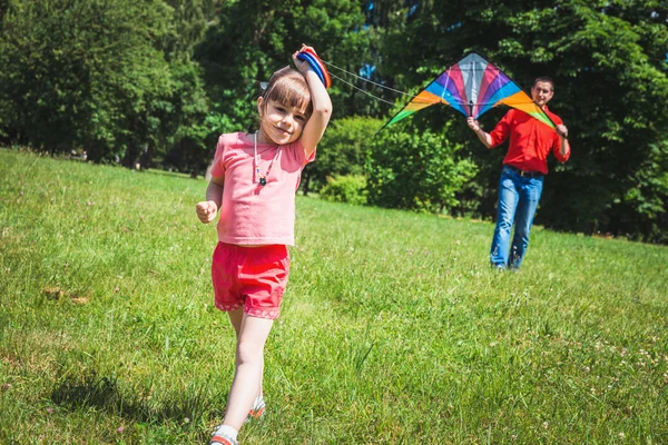 A menina e seu pai brincam com um papagaio . — Fotografia de Stock