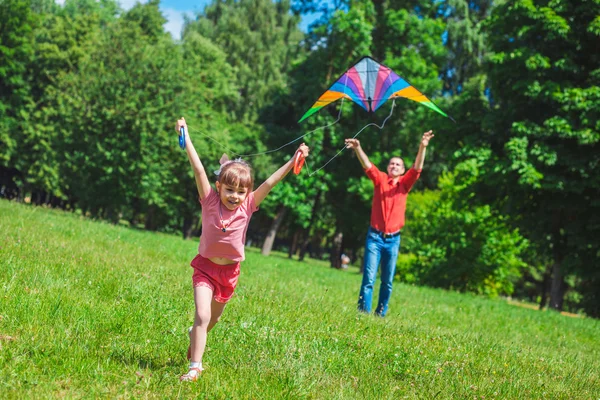 Het meisje en haar vader spelen met een vlieger. — Stockfoto