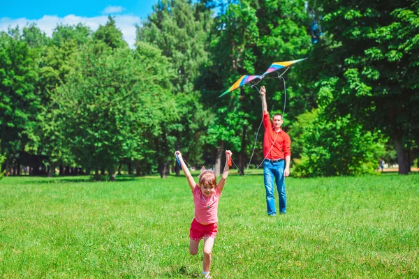 A menina e seu pai brincam com um papagaio . — Fotografia de Stock