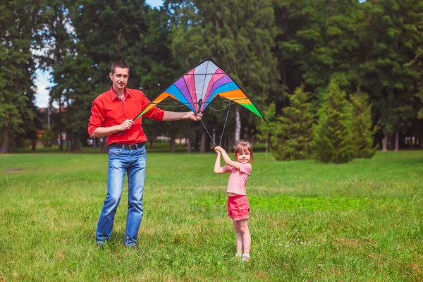 Het meisje en haar vader spelen met een vlieger. — Stockfoto