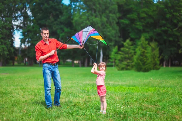 Het meisje en haar vader spelen met een vlieger. — Stockfoto