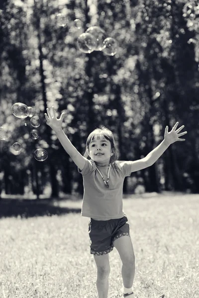 Little girl playing with soap bubbles — Stock Photo, Image