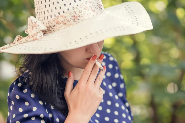 Vrouw in een hoed roken — Stockfoto