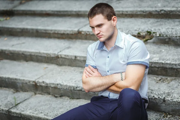 Schöner Kerl im blauen Hemd sitzend — Stockfoto