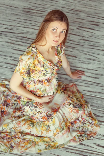 Pregnant woman in dress sits on the floor — Stock Photo, Image