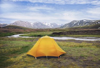 Turuncu bir çadır kamp ve İzlanda da trekking bir nehir kıyısında 