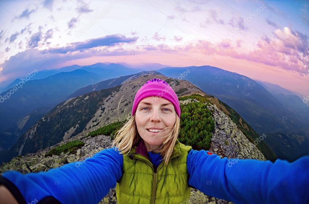 Smiling young woman takes a selfie  on  the  top of   mount Great Sivulja