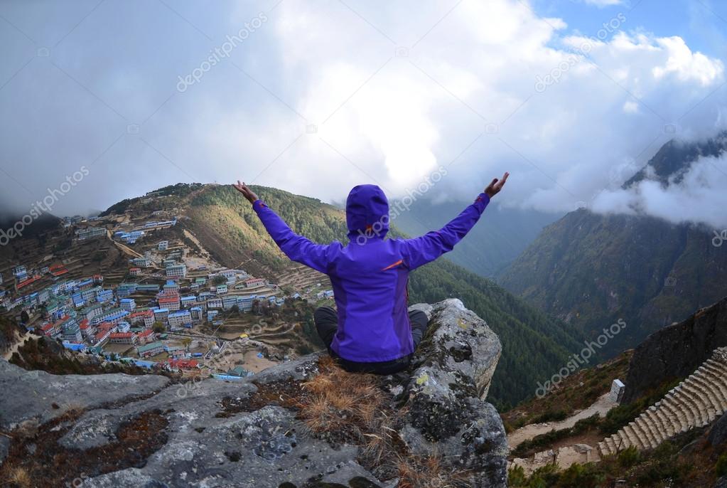 Young woman  on a stone   with raised hands