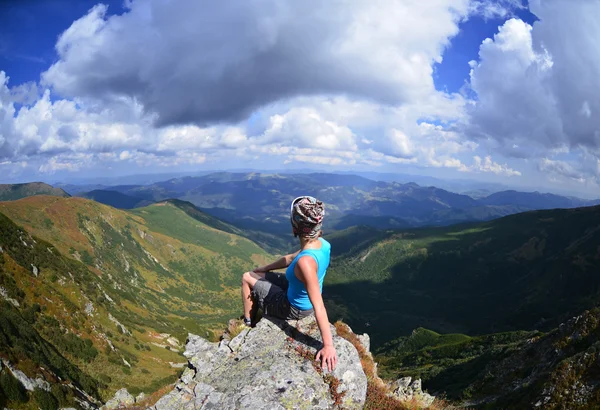 Junge Frau sitzt auf einem Stein in den Bergen — Stockfoto