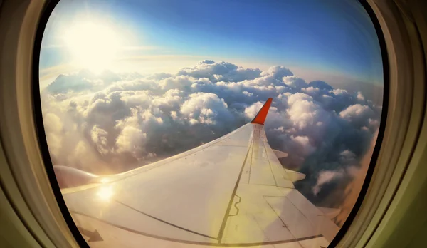 Nubes y cielo visto a través de la ventana de un avión — Foto de Stock