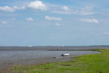 Kuzey Denizi kıyıları sular çekildiğinde. Çamurda lastik bir sandal yatıyor..