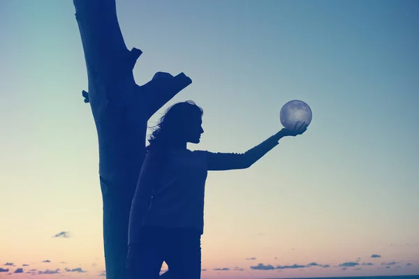 Dziewczyna trzyma księżyc w rękach. Zachód słońca nad morzem. Marzenia się spełniają.. — Zdjęcie stockowe