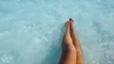 Dalgalarla dolu bir havuzda dinlenen bir kadın. Bronzlaşmış kadın bacaklarının üst görüntüsü