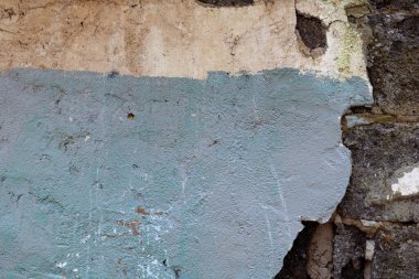 Üstü çimentoyla kaplanmış eski bir tuğla duvar.