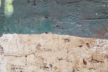 Üstü çimentoyla kaplanmış eski bir tuğla duvar.