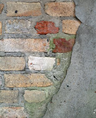 Üstü çimentoyla kaplanmış eski bir tuğla duvar.