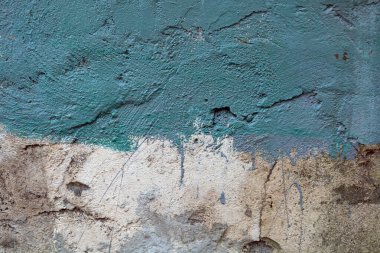 Üstü çimentoyla kaplanmış eski bir tuğla duvar.