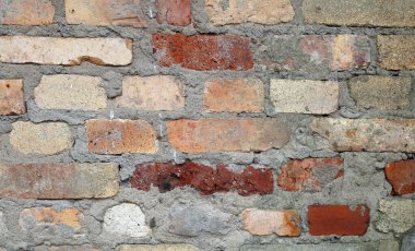 Üstü çimentoyla kaplanmış eski bir tuğla duvar.