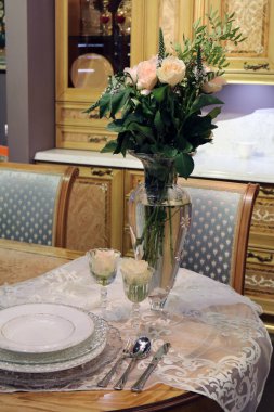 Ahşap bir mutfakta, arka planda çiçekli vazo.