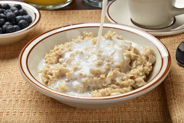 Milk poured in bowl of oatmeal — Stock Photo, Image