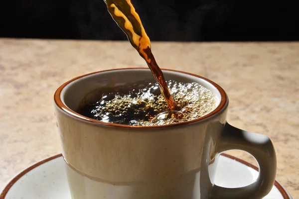 Наливание черного кофе в чашку — стоковое фото