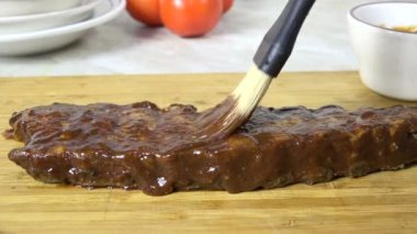 Kaburgaların üzerine barbekü sosu sürüyorum.