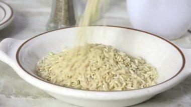 Kahverengi pirinci ağır çekimde bir kaseye boşaltıyorum.